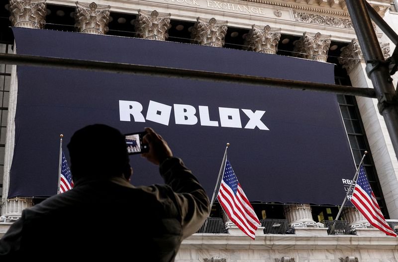 © Reuters. A man photographs a Roblox banner displayed, to celebrate the company